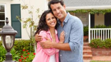 Woman and man hugging in front of their home